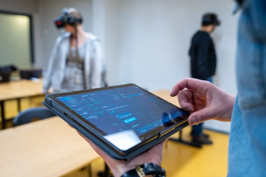 En surfplatta styr en VR-session medan två elever bär headset i ett klassrum