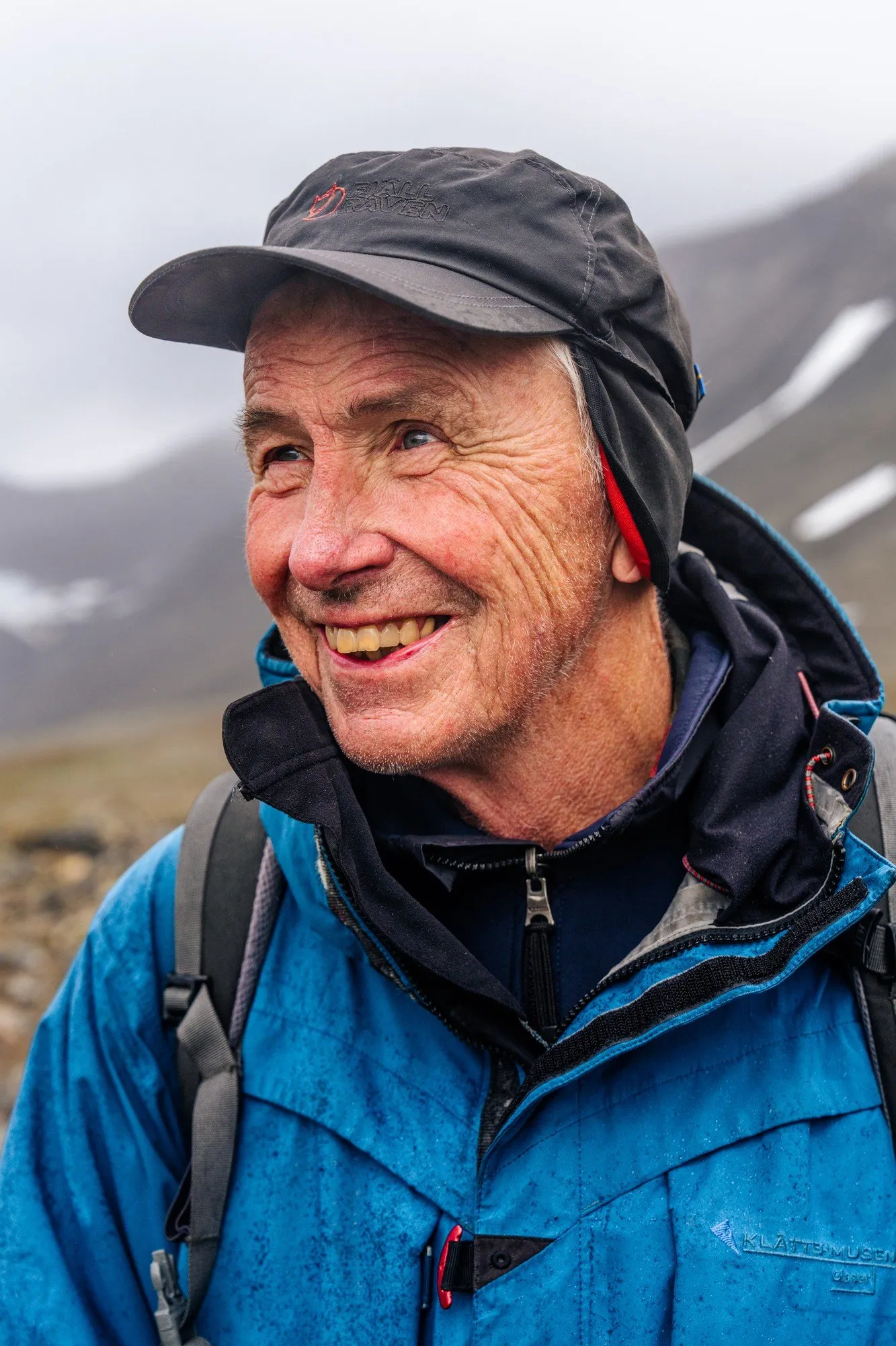 Glaciologen Per Holmlund ler i Tarfaladalen, med snöfläckiga berg bakom sig
