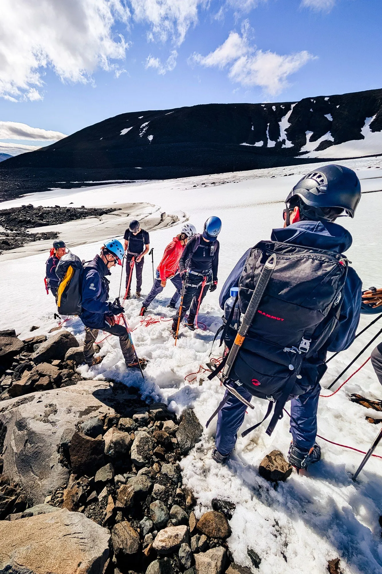 Ett replag i hjälmar klättrar ner från moränen ut på glaciärens snö