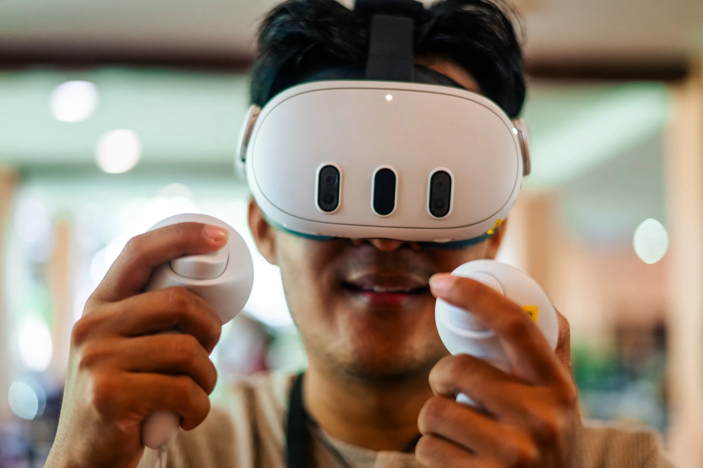 En workshopdeltagare med VR-headset och två handkontroller, leende
