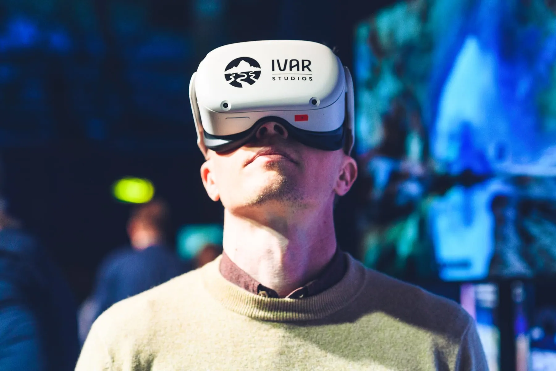A visitor wearing a VR headset with the IVAR Studios logo