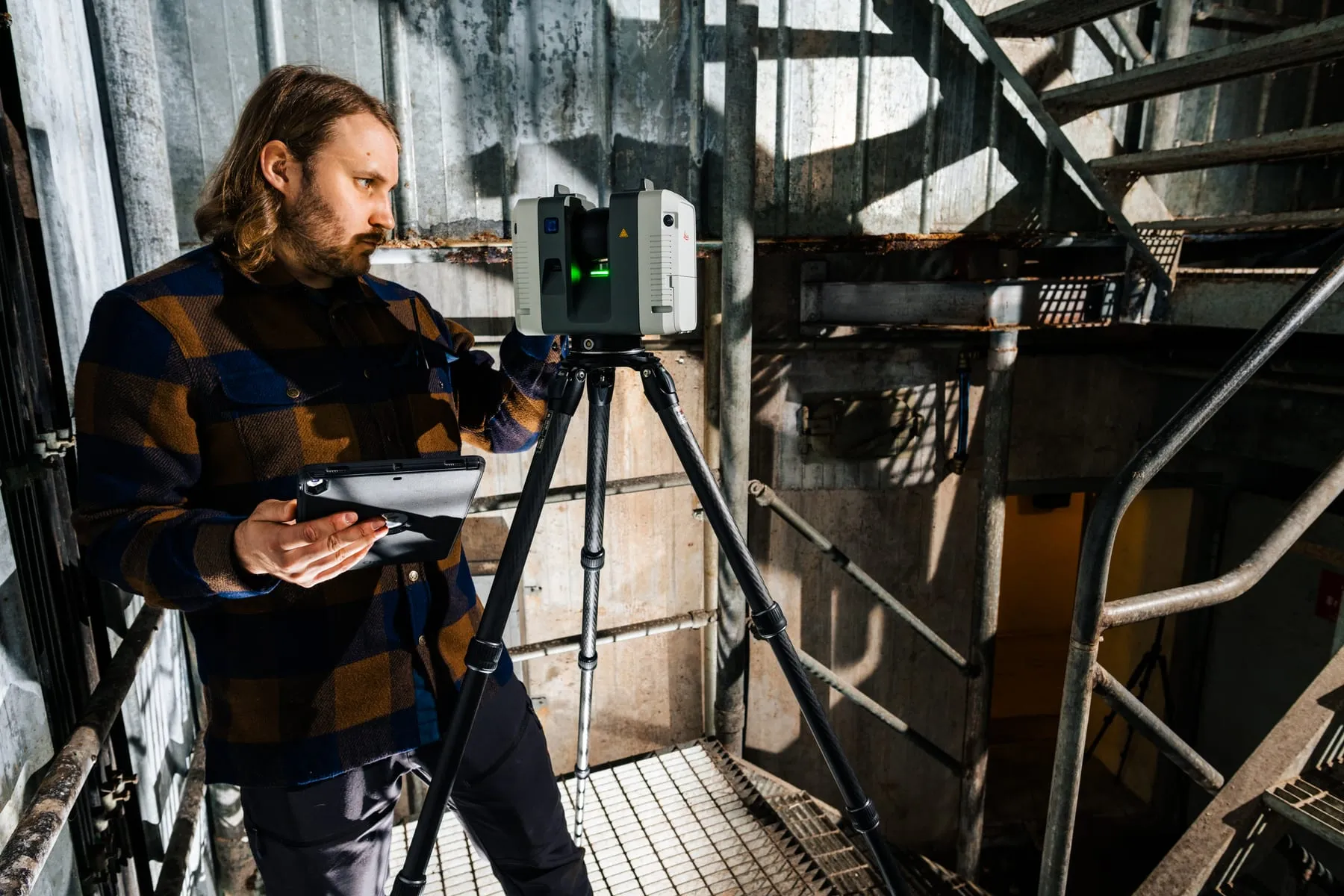 A laser scanner on a tripod in a steel stairwell, run from a tablet